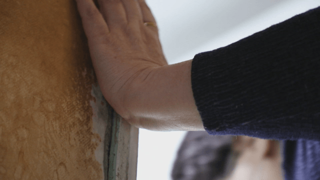 Person who turns on light and enters room with old wallpaper