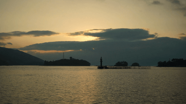 Sunset over a calm sea with a lighthouse