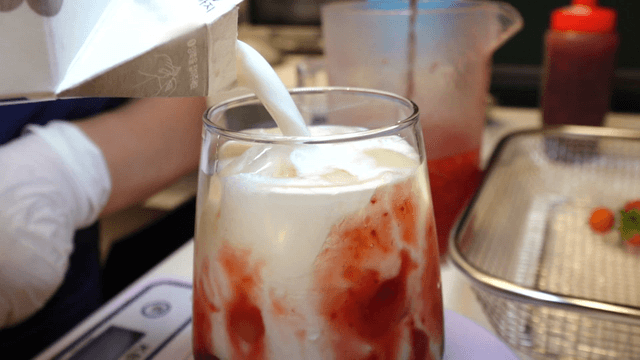 Strawberry latte being made in a glass cup