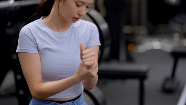 Young woman checking injured wrist in gym