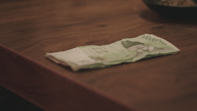 Hand placing Korean money on a table