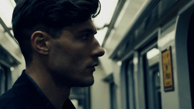 A man in a subway train looking thoughtful