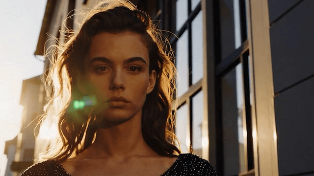 A woman standing down a sunlit street