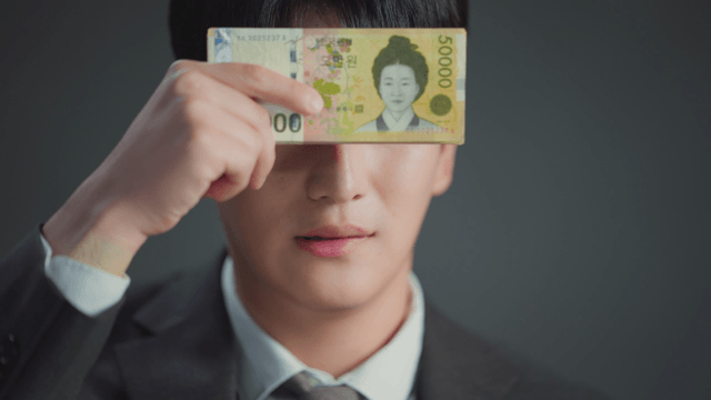Man showing mixed expressions while covering his face with money
