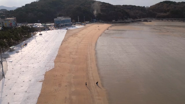 A quiet beach with a few people walking