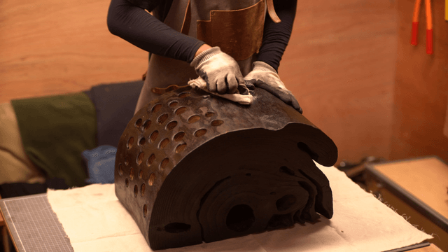 Artisan polishing a black wooden sculpture with a cloth