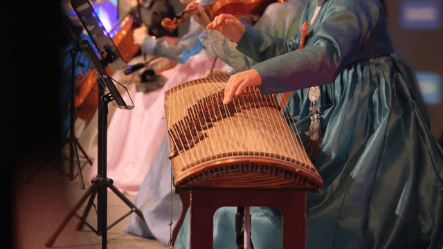 Playing a gayageum in a traditional ensemble