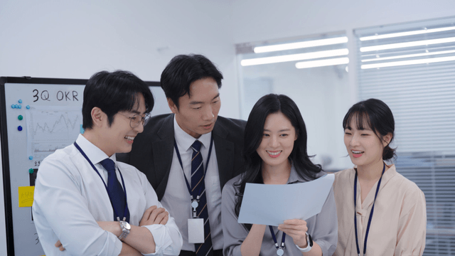 Team members standing and smiling while reviewing meeting documents