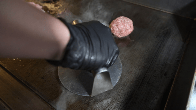 Burger patty pressed on hot grill