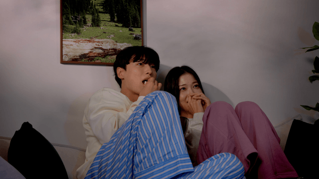 Couple watching scary movie on living room sofa
