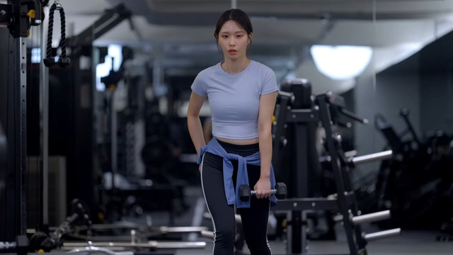 Young woman doing lunges with dumbbells at gym