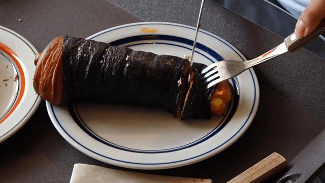 접시에 놓인 김밥 모양 빵을 자르는 사람