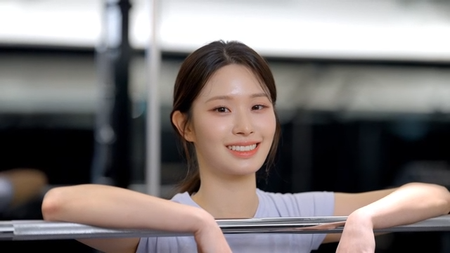 Young woman smiling while resting on a barbell at the gym