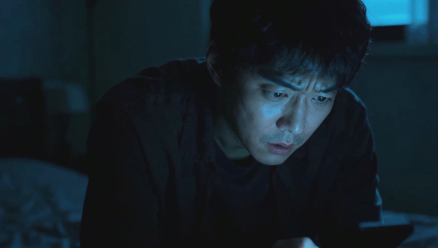 Man focused on his phone in a dim room