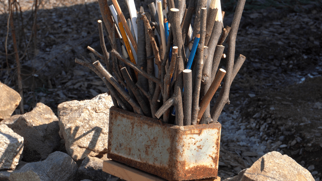 Wooden pencil sculpture placed on stone wall