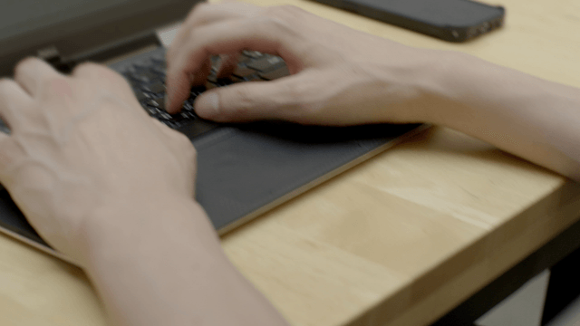 Hands typing on a laptop keyboard