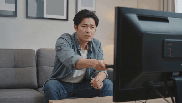 Man using broken TV remote in living room