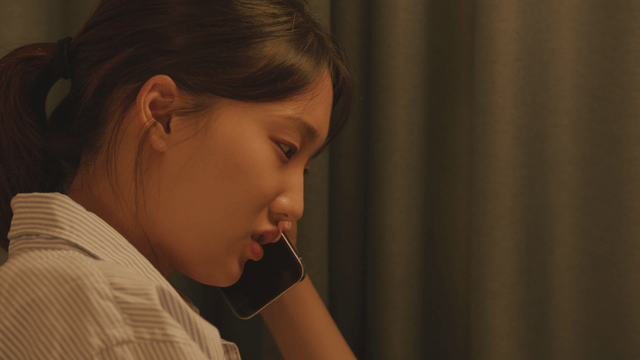 Woman talking on the phone next to a curtain