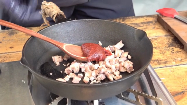 A spoonful of red chili paste added to the pork