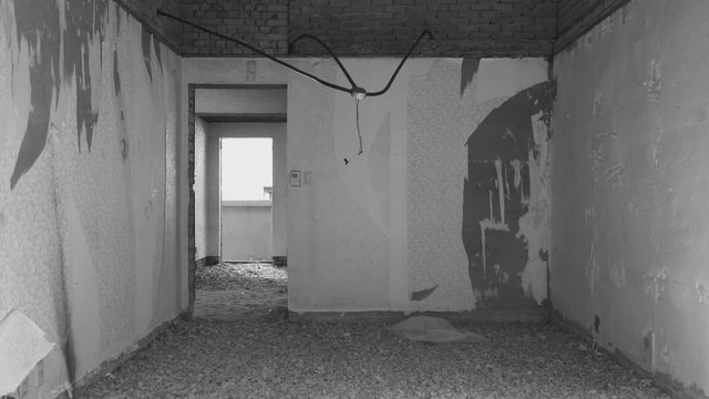 Empty room with gravel floor and torn wallpaper