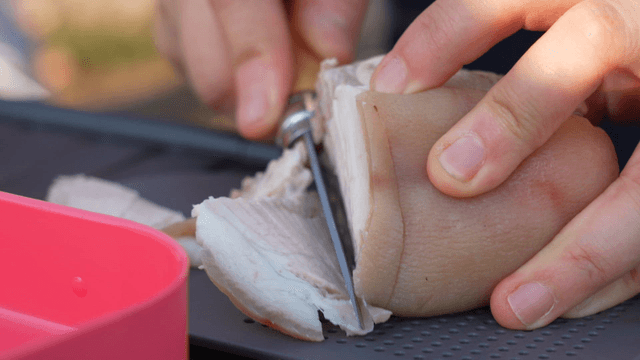 Boiled pork slices being cut on a chopping board