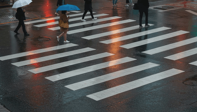 People crossing rainy road crosswalk