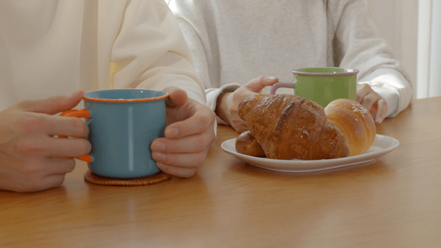 Croissants and salted rolls arranged on dining table with mugs