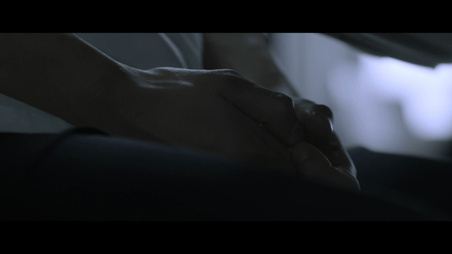 Anxious hands clasped between knees