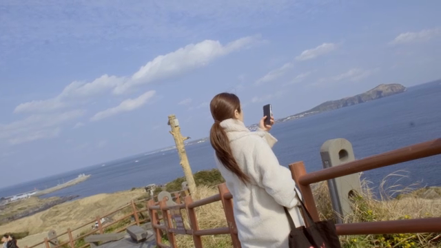 Woman taking a picture of the seascape with her smartphone