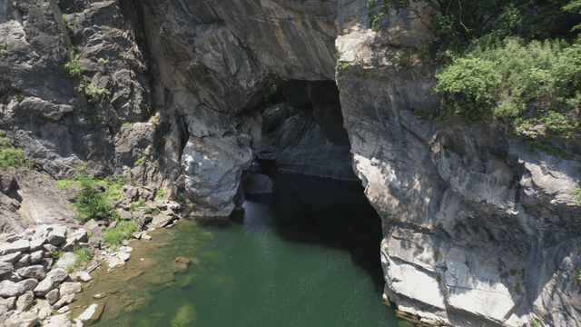 Clear valley water beneath rocky cliff