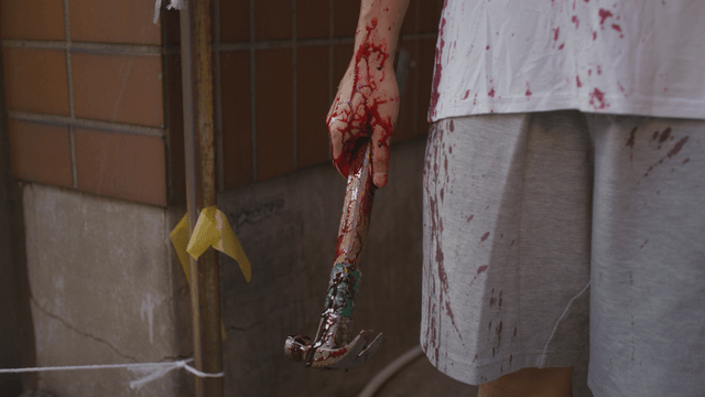 Hand holding a blood-stained hammer and clothes