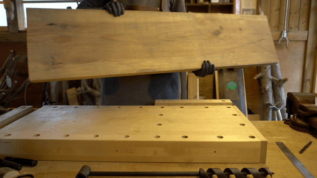 Carpenter handling a large wooden board in a cozy workshop
