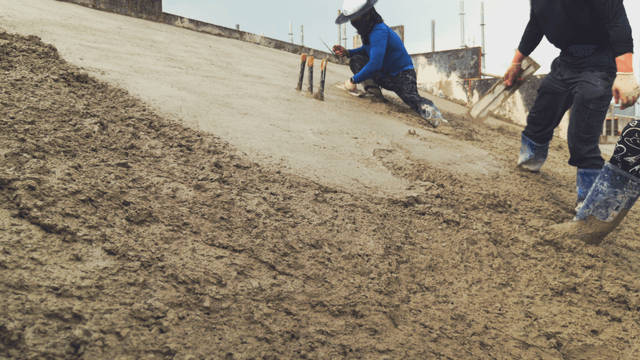 Workers smoothing wet concrete on a slope
