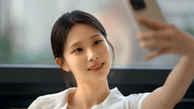 Young woman taking a selfie by the window