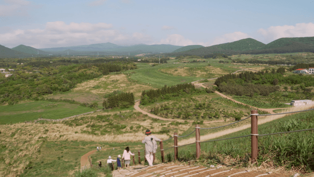 People descending Jeju oreum volcanic cone under clear sky