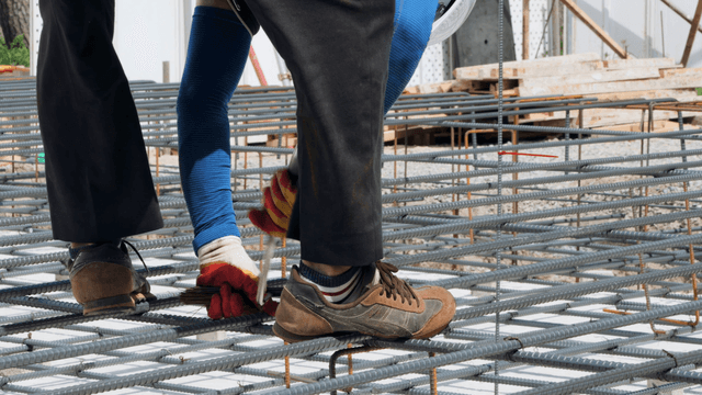 Worker walking on steel rebar at a construction site