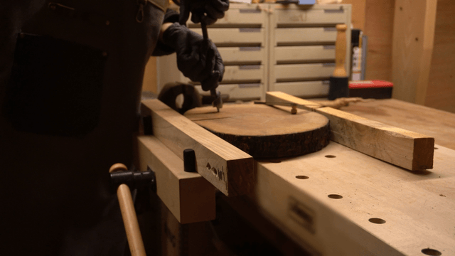 Artisan drilling a wooden board with a hand drill