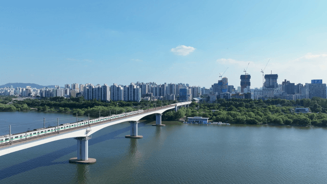 Train crossing bridge over Han River with city skyline