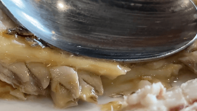 Spoon pressing juicy grilled cutlassfish