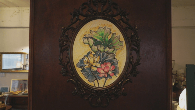 A framed floral painting on a wooden wall
