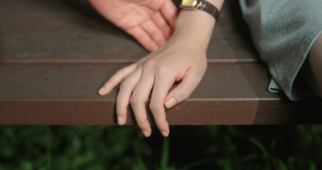 Two people holding hands on a bench