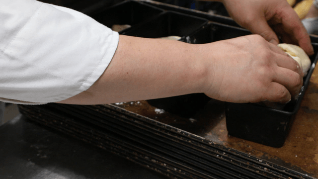 Baker preparing dough in baking pans