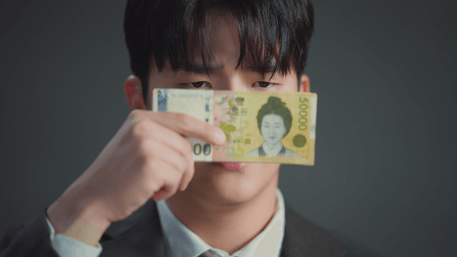 Man showing mixed expressions while covering his face with money