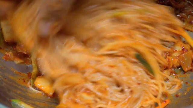 Spicy noodles being mixed in a bowl