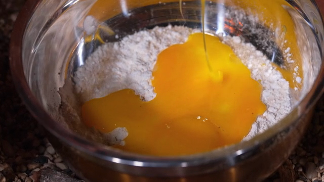 Eggs being poured into flour in a bowl