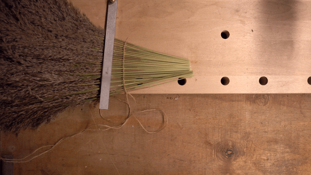 Person trimming reeds on a workbench
