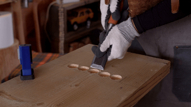 Woodworking with chisel and gloves