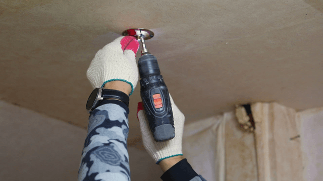 Person installing a smoke detector on the ceiling