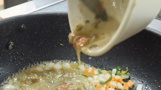 Crab Innards Being Poured into Pan with Vegetables