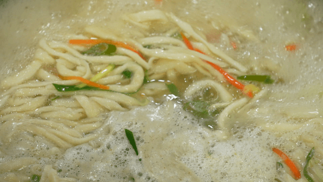 Noodle soup boiling with vegetables